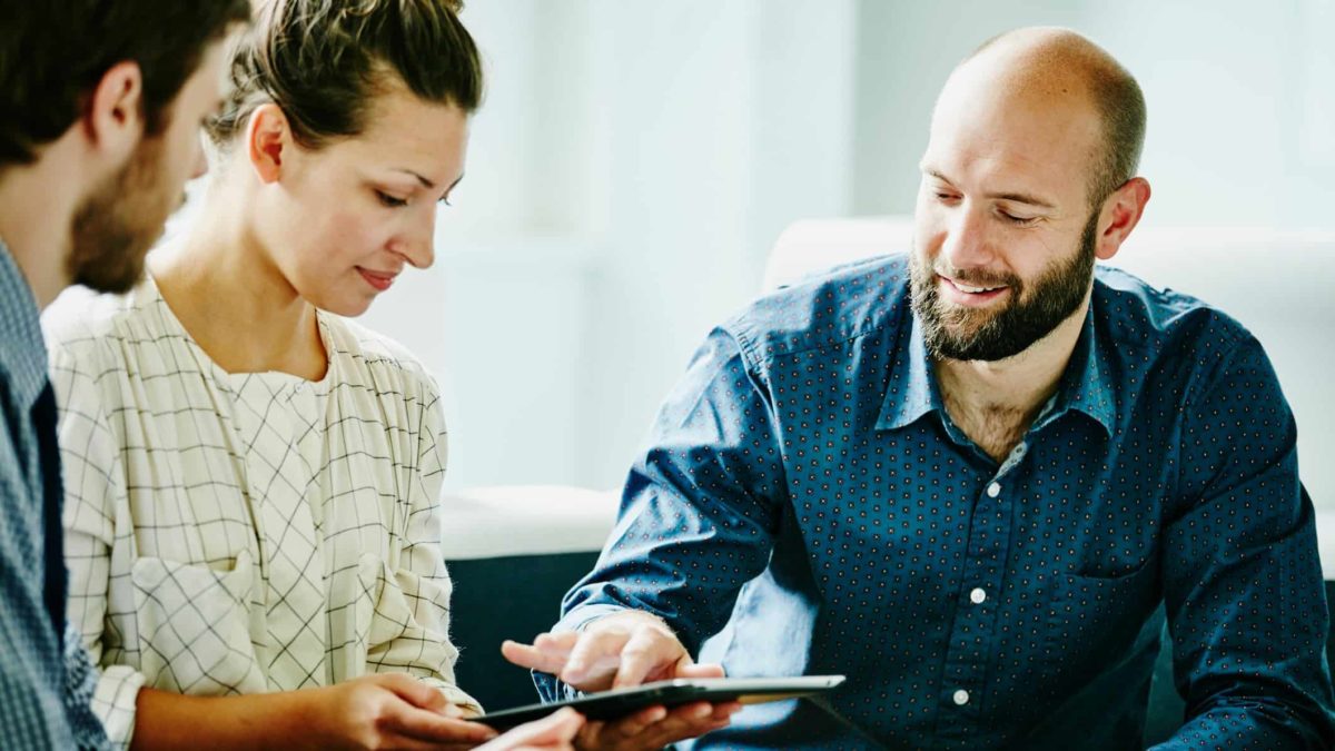 man helping couple use a tablet