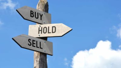 Buy, hold, and sell ratings written on signs on a wooden pole.