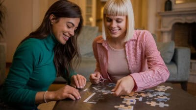 Two smiling women doing a jigsaw puzzle.