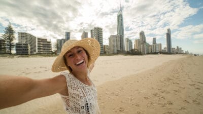 Joyful woman at a beach on the Gold Coast with her arms spread out.